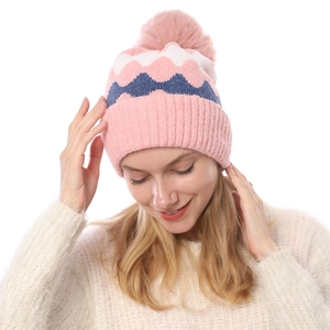 Detail der Strickmütze mit Wellenmuster und flauschigem rosa Bommel für den Winter