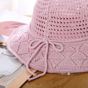 Detail of pink knitted sun hat showing diamond hollow pattern and bow decoration