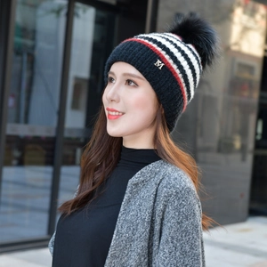 Detail der Strickmütze mit schwarz-weiß-roten Streifen und flauschigem Kunstfellbommel