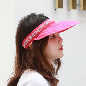 Close-up of pink sun visor with silver chain pattern and quilted polka dot brim