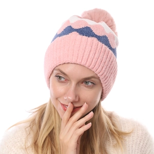 Detail der weichen Chenille-Strickmütze mit rosa Bommel und Wellenmuster-Textur