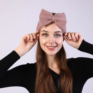 Detailed view of pink knitted headband with a large bow showing soft winter texture