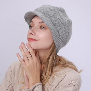 Close-up of light grey knit peak cap with soft herringbone pattern and warm texture