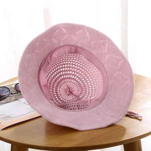 Detailed knit texture and wide brim of pink summer beach hat on a wooden table