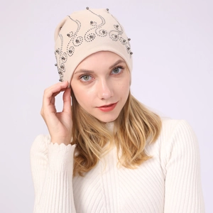 Detail of cream cotton beanie with elegant silver rhinestone vine pattern decoration