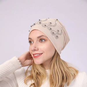 Detail of beige cotton beanie featuring elegant silver rhinestones and grey bead patterns