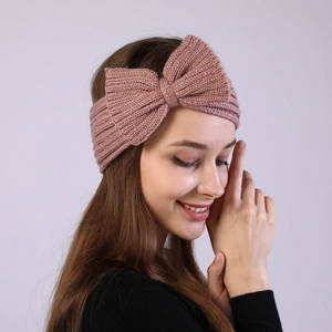 Detail of pink knitted bow headband with thick ribbed texture on a female model