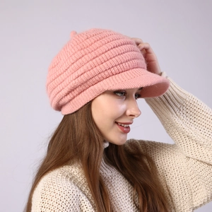 Close-up of pink striped knit beret cap with peak and pompom for women winter