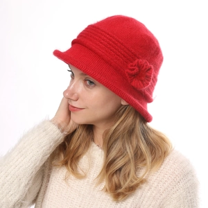 Detail view of red knitted cloche hat featuring a floral accent and soft wool texture