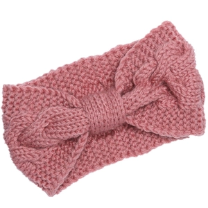 Close-up detail of pink chunky knit headband with bow design and soft wool texture