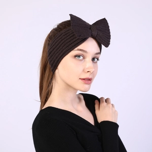 Detailed side view of a coffee brown knitted bow headband on a model for winter