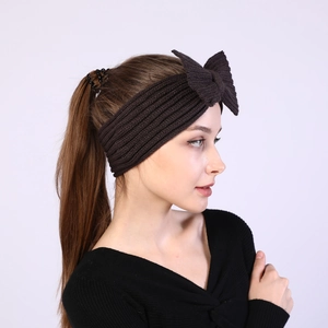 Detail of dark brown knit headband with large bow showing ribbed texture on model