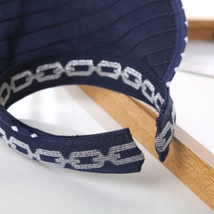 Macro shot of silver chain embroidery and white polka dots on navy sun hat fabric