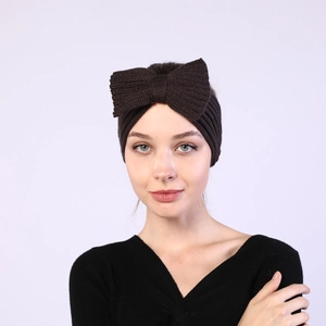 Detail view of a thick dark brown knitted headband featuring a large bow knot texture