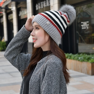 Outdoor-Streetstyle-Ansicht einer grauen Strickmütze mit Bommel und M-Logo-Detail