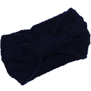 Detail of navy blue cable knit headband with twisted bow design for winter warmth