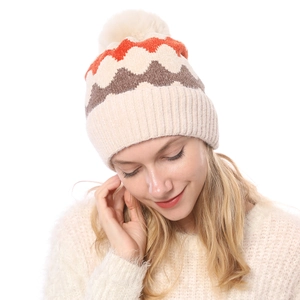 Detailansicht der warmen Chenille-Stricktextur mit orangefarbenem Wellenmuster und Bommel