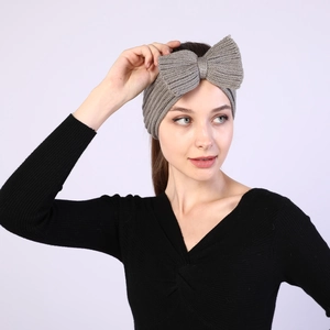 Close-up of grey knitted headband with large bow worn by model for winter warmth