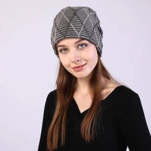 Detail of grey knitted beanie showing thick geometric diamond weave texture on model