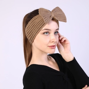 Close-up of brown knitted headband with large bow detail worn by a model in winter