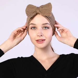 Macro detail of camel knitted headband featuring a prominent bow design for winter warmth