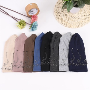 Flat lay of cotton beanies in eight colors with elegant pearl beadwork on white background