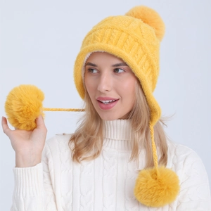 Dettaglio cappello in maglia di ciniglia gialla con fodera in peluche e grandi pompon caldi