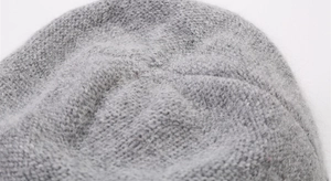 Close-up detail of soft fuzzy knit texture on a warm grey winter bucket hat for women