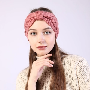 Detail of pink knitted headband with twist texture worn by a model in winter style