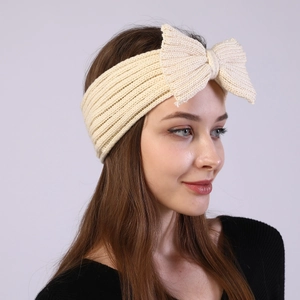 Detailed close-up of cream knit headband featuring a large bow and ribbed texture