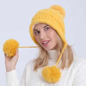 Dettaglio del cappello in maglia giallo con morbida fodera in pile e pompon di pelliccia