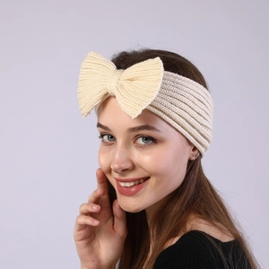 Close-up of beige knitted bow headband for women featuring vertical ribbed texture