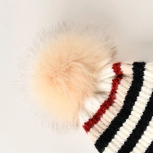 Detailansicht der Strickmütze mit bunten Streifen und großem flauschigem Kunstfellpompon