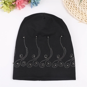 Close-up of black cotton beanie with silver beaded wave pattern on white background