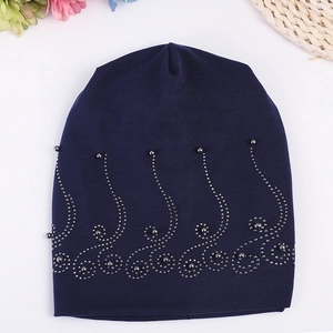 Detail of dark blue cotton beanie featuring elegant rhinestone wave and pearl decoration
