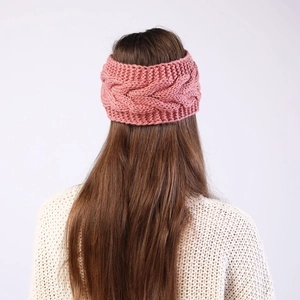 Rear view of a pink cable knit headband showing the thick twisted texture on a model