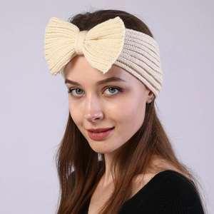 Close-up of a model wearing a cream-colored knitted bow headband for autumn and winter