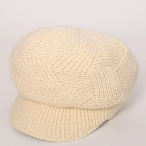 Detailed close-up of cream knit newsboy cap showing geometric texture and short brim