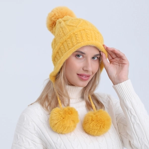 Dettaglio del cappello in maglia gialla con pompon in ecopelliccia e fodera calda