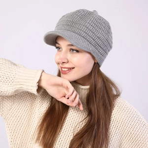 Detail of grey cable knit newsboy hat with peak showing thick warm texture