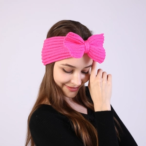 Detail of pink knitted headband with a large bow showing ribbed texture on model