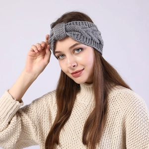 Close-up of a grey knitted headband with twist knot design on a female model