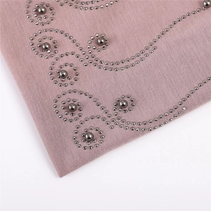 Close-up of pink cotton fabric featuring elegant pearl and rhinestone scroll pattern