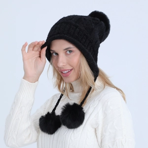 Dettaglio del cappello invernale nero in maglia con pompon e paraorecchie morbidi