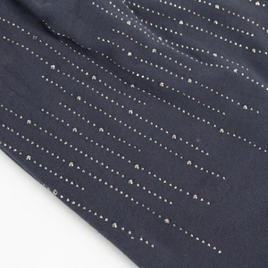 Macro view of dark navy knit fabric featuring precise silver rhinestone ornamentation