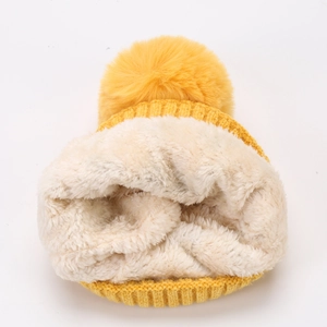 Detail der gelben Strickmütze mit dickem weißem Teddyfutter und flauschigem Pompon
