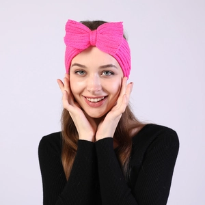 Detail of rose pink knitted headband with bow decoration on model for winter warmth
