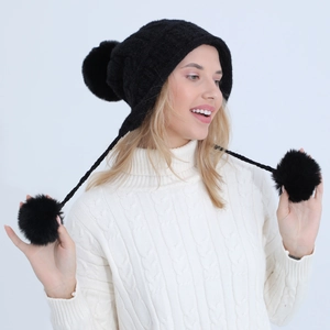 Dettaglio cappello in maglia nera con pompon in ecopelliccia e paraorecchie a treccia