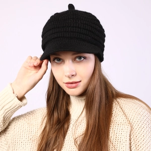 Detail of black striped knit newsboy hat with warm fleece lining and top pom-pom decor