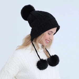Dettaglio del cappello invernale nero con tre pompon in finta pelliccia e paraorecchie